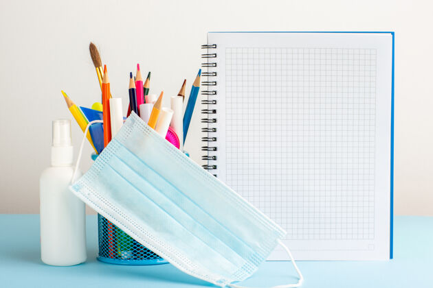 铅笔正面视图不同的彩色铅笔与文案和喷雾蓝色的书桌上日记喷涂笔记本