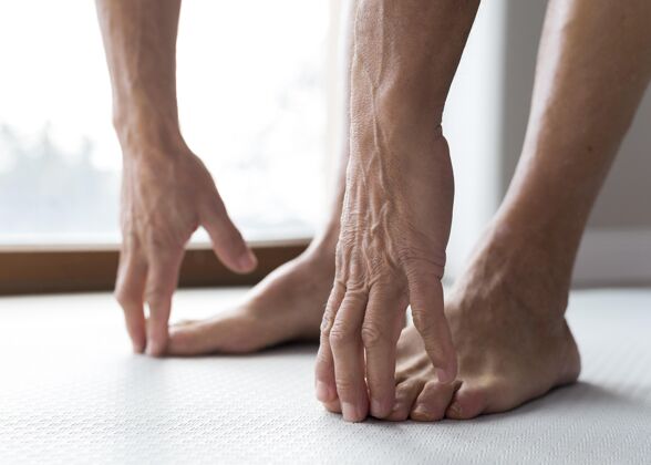 老年健身闭上一个老人的腿和手运动成熟老年人