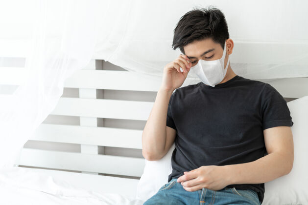 病毒传播亚洲男子戴口罩以防在检疫室因冠状病毒冠状病毒-19而感到头痛和咳嗽14天亚洲人紧张