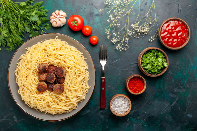 配料俯瞰煮熟的意大利面食 在深蓝色的表面有肉丸调味料和绿色晚餐调味料意大利面