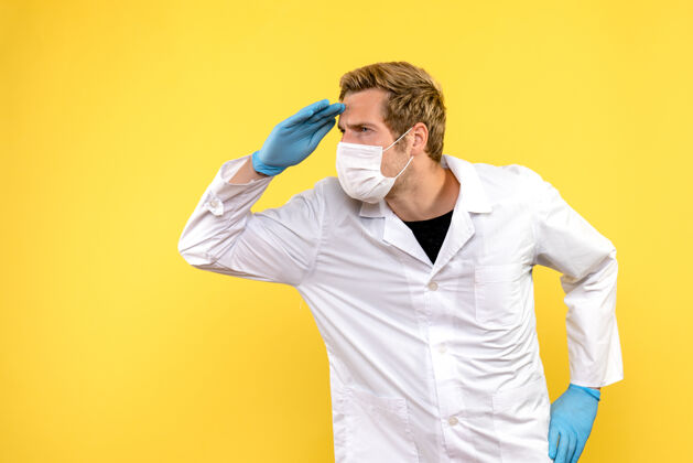 医生正面图黄色背景上的男医生正在看远处的大流行科维德健康医生成人冠状病毒商人