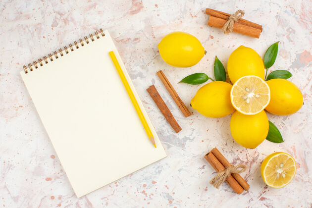 顶部顶视图新鲜柠檬切柠檬肉桂棒笔记本和黄色铅笔明亮孤立的表面肉桂光明柑橘
