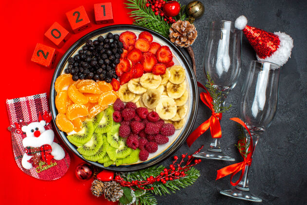 新鲜水果收集新鲜水果圣诞袜圣劳斯帽数字glaus酒杯在黑暗的背景俯视图饮食圣诞老人高脚杯