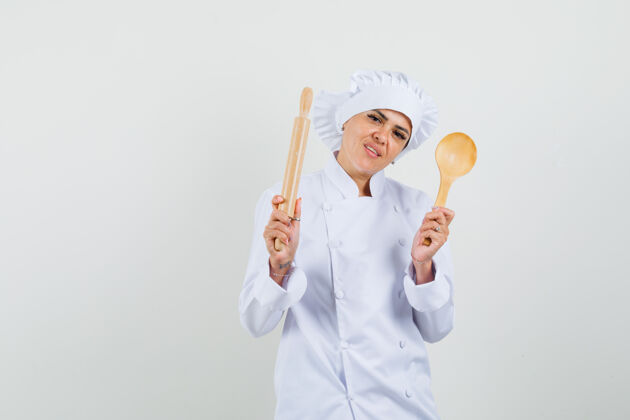 餐厅女厨师手拿擀面杖和木勺 穿着白色制服 看上去很自信专业烹饪柜台