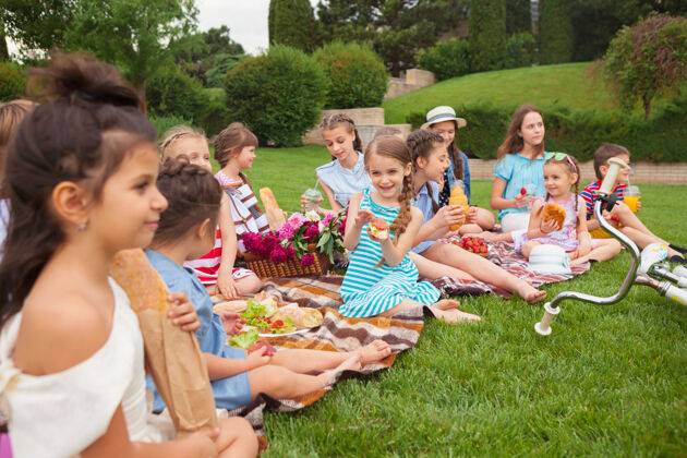 年轻儿童时尚概念一群少女坐在公园的绿草地上变化年轻服饰