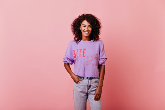 黑色自信迷人的女孩站在口袋里 手放在口袋里害羞的非洲女士在紫色衬衫工作室肖像时尚情感美国人