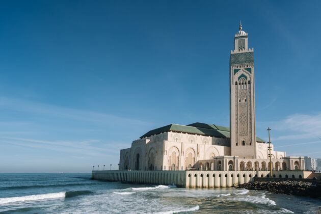 塔在蓝天和阳光下 哈桑二世清真寺被水和建筑物包围东方清真寺寺庙