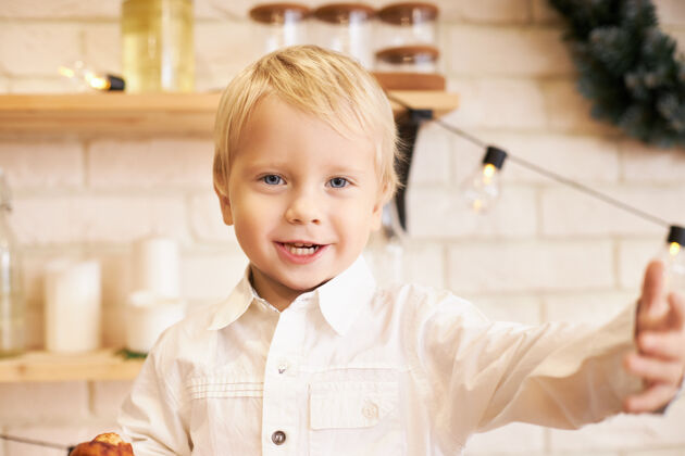 童年快乐 休闲和积极的情绪情绪化的可爱小男孩的肖像 穿着白衬衫 积极地做着饥饿的手势 午饭前吃零食 说些什么 在舒适的厨房里摆姿势孩子小美味