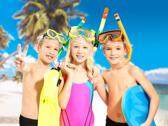 兄弟快乐的孩子们在海滩上玩耍的画像小学生们穿着鲜艳的泳装 头戴游泳面罩站在一起一起生活泳装