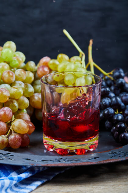 天然一堆葡萄和一杯果汁放在陶瓷盘子上 特写盘子葡萄餐桌