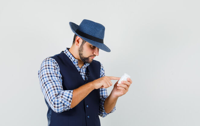 衬衫年轻人穿着衬衫 背心 戴着帽子 看着一瓶药的信息自信休闲阅读