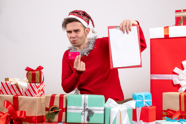 剪贴板前视图年轻人拿着卡片和剪贴板围坐在圣诞节礼物销售包盒子