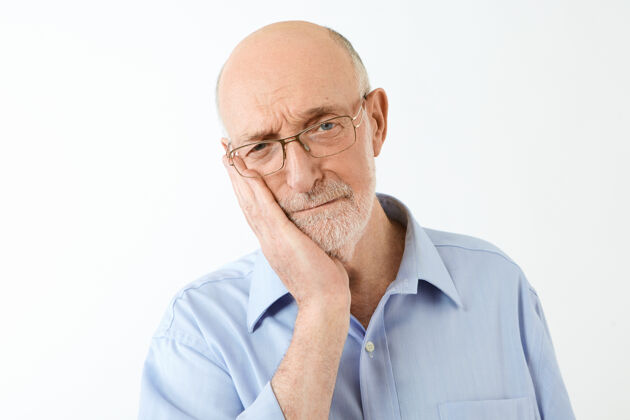脸颊年龄和成熟的人的概念孤独的镜头沮丧的欧洲男性退休者光头和浓密的胡须接触脸颊 患有无法忍受的牙痛 有痛苦的表情触摸成熟偶然