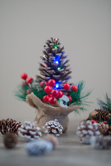 装饰木桌上装饰着冬青浆果和灯光的松果松树传统雪花