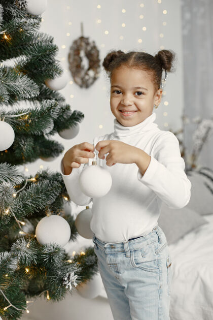 盒子穿白色毛衣的孩子站在圣诞树旁的女儿节日年轻传统