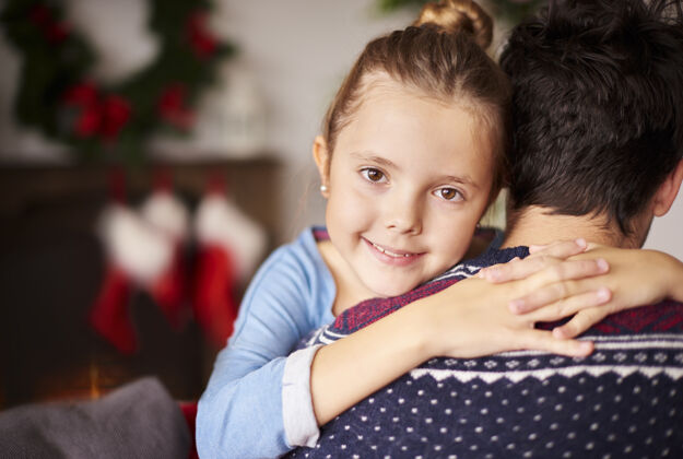 室内小女孩抱着她的父亲结合家庭圣诞装饰