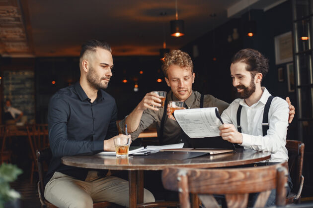 成人谈判中的商人坐在桌边喝酒的男人朋友们在聊天专业人士经理胡须