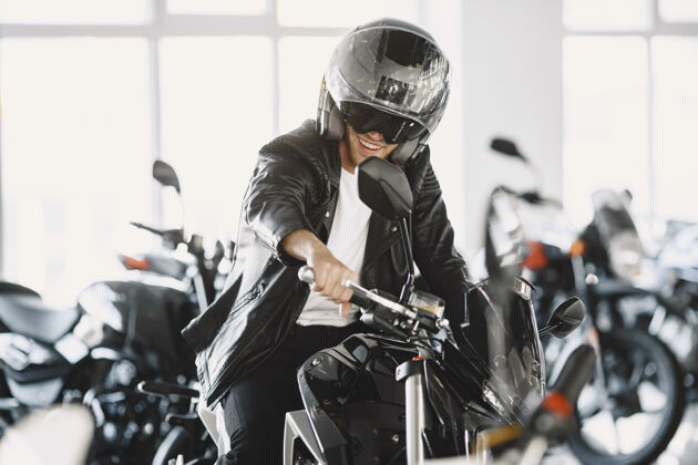 客户一个男人在摩托店里选摩托车一个穿黑夹克的男人一个戴头盔的男人运输车辆摩托车