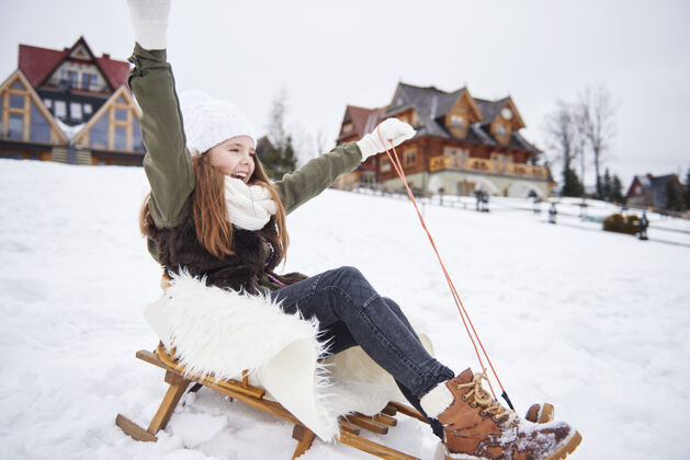 兄弟姐妹手举在雪橇上的女孩绳子温度冬天