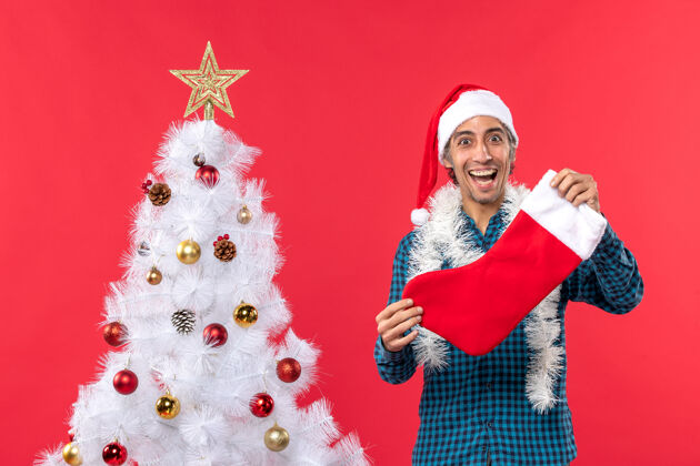 帽子一个戴着圣诞老人帽子 穿着蓝色条纹衬衫的激动 快乐 情绪化的年轻人袜子圣诞庆祝