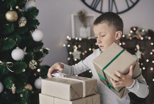 堆叠站在圣诞树旁拿礼物的男孩盒子圣诞节生活