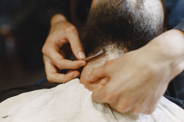 黑发有胡子的男人有客户的理发师刮胡子的男人摩登商店剃须