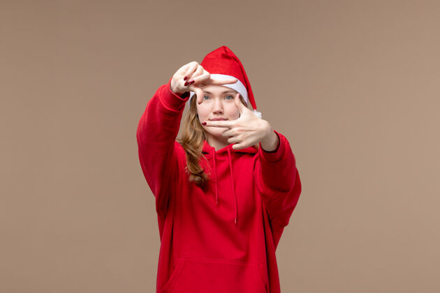 快乐正面图圣诞女孩在棕色背景上微笑着摆姿势圣诞感慨微笑帽子快乐