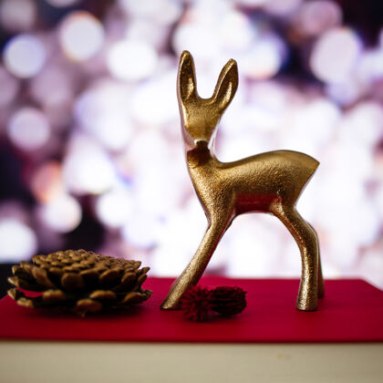 季节一只小鹿的特写镜头和一个松果在一本书上 背景模糊 灯光昏暗圣诞树季节性圣诞节