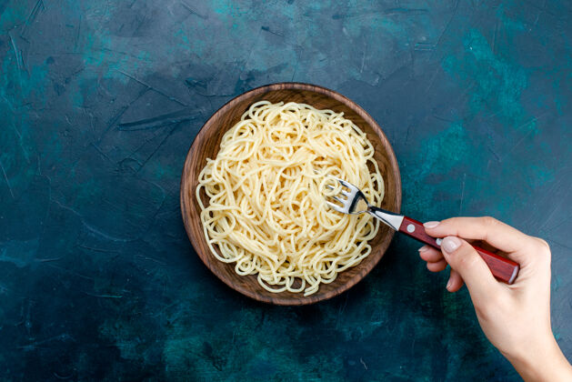 深蓝色俯视煮熟的意大利面食内圆木板上的深蓝色背景意大利面食意大利餐面团肉意大利内部面食