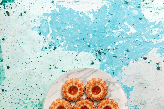 灯光俯视美味饼干圆形与果酱形成的浅蓝色背景饼干甜甜饼干蛋糕内板顶部饼干成型的