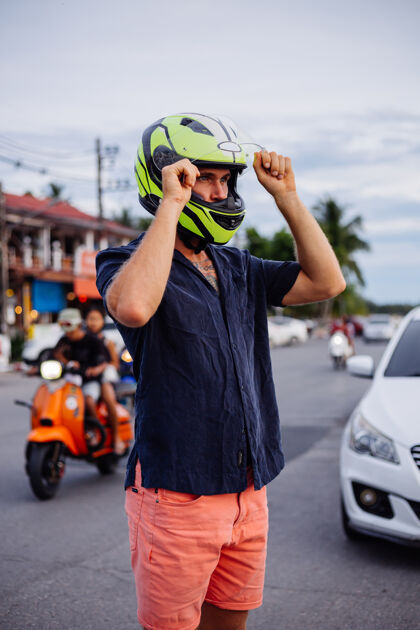 户外日落时分 在泰国繁忙的公路边 一位戴着黄色头盔的男子的画像时尚车辆速度