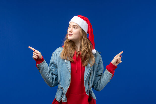 年轻正面图蓝色桌子上戴着红色圣诞帽的年轻女性圣诞情感色彩颜色年轻女性蓝色