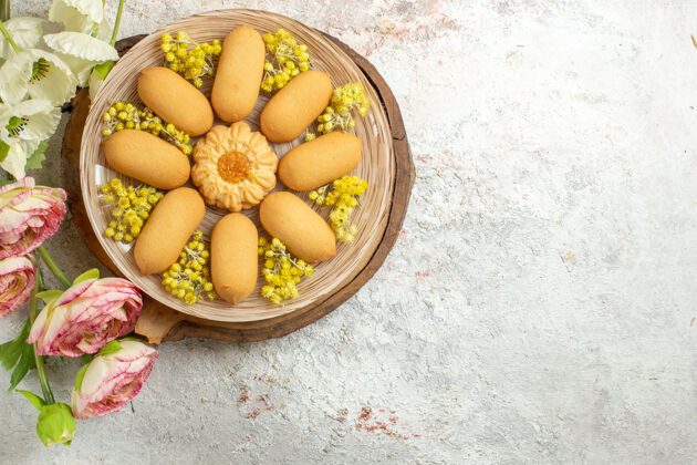 盘子一盘饼干放在木盘上 花放在大理石的左边维生素顶视图可食用水果