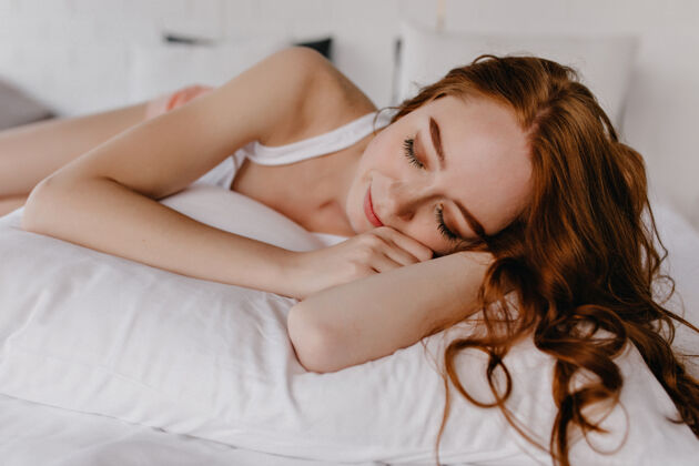 女人美丽的卷发女郎睡在自己的房间里迷人的白人女孩躺在枕头上闭着眼睛快乐醒早
