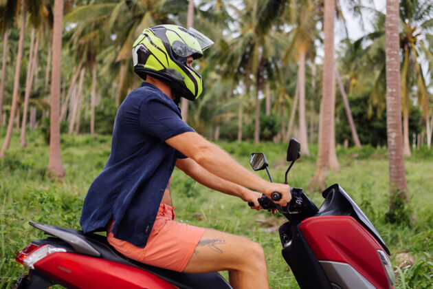 车辆在热带丛林的田野上纹着红色摩托车的壮汉服务户外自由