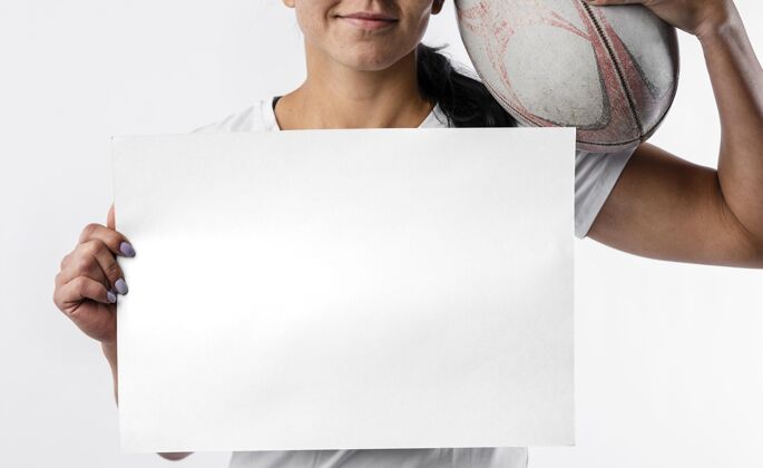 运动员女橄榄球运动员手持空白标语牌和球的前视图活动联盟锦标赛