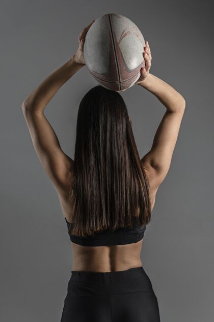 活动女橄榄球运动员与球合影的后视图垂直足球完全接触