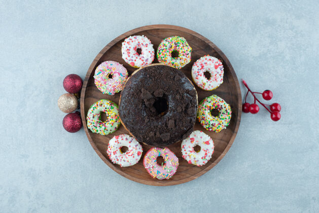 烘焙食品节日装饰品和一盘小甜甜圈围绕着一个 大理石上的大甜甜圈上釉货物圣诞节
