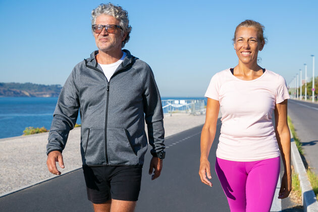 运动两个成熟的慢跑者早上跑步后沿着河岸散步正面视图 中景运动和退休概念男人成人跑步者