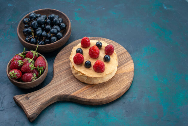 小正面图小蛋糕烘焙圆与新鲜草莓形成的深蓝色表面蛋糕烘焙甜糖面团馅饼橄榄木制勺子早餐