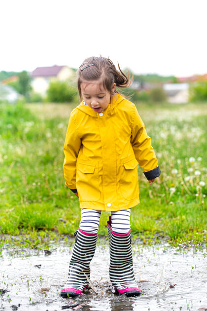 靴子可爱的小女孩跳进水坑无忧无虑的童年散步女孩自然