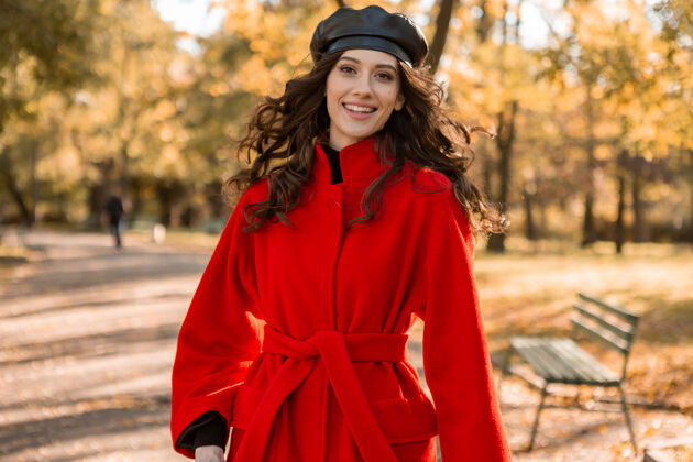 时尚迷人的时尚微笑的女人卷发漫步在公园穿着温暖的红色外套秋季时尚 街头风格 戴贝雷帽苗条黄色阳光