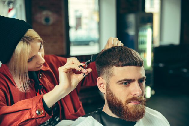 时尚客户在理发店剃须女理发师在沙龙性别平等女性在男性职业美容刀片胡子