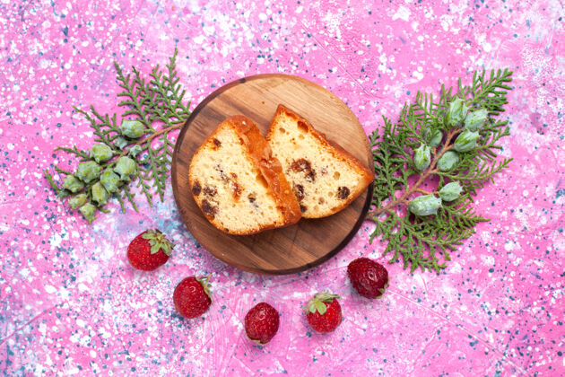 美味美味蛋糕的俯视图甜美可口 粉红色表面上有新鲜的红色草莓切片装饰饼干维管植物