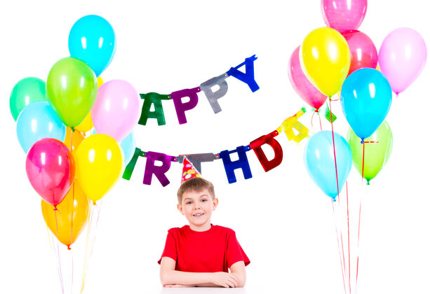 男孩快乐的小男孩坐在桌子旁 在一个生日聚会上玩得很开心-被隔离在一个白色的房间里孩子庆祝衬衫