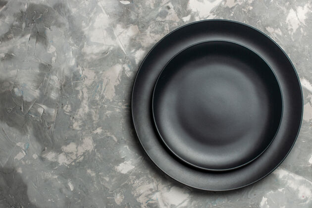 炒锅灰色表面上黑色的圆形空盘子俯视图餐具平底锅食物