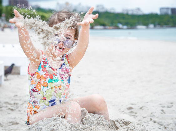 沙滩戴着太阳镜的可爱小女孩在沙滩上玩海砂孩子岸边时尚