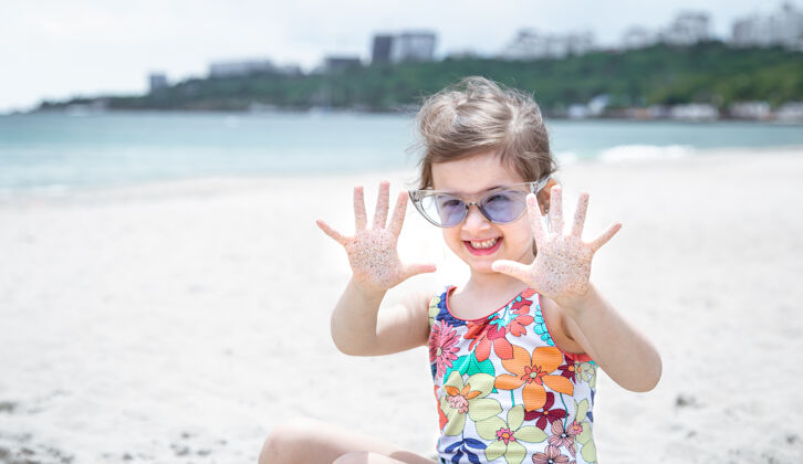 自然一个戴眼镜的可爱小女孩正在海边的沙滩上玩女孩娱乐孩子
