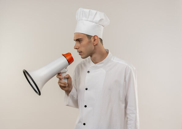 厨师站在侧视图年轻男厨师穿着厨师制服在扬声器上讲话与复制空间穿着个人资料男