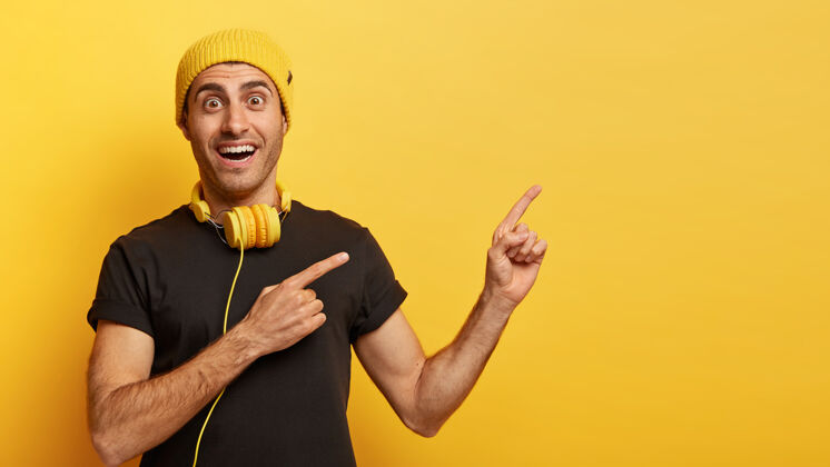 笑快乐的潮人用两个食指指着旁边 为你的广告内容做广告侧听手